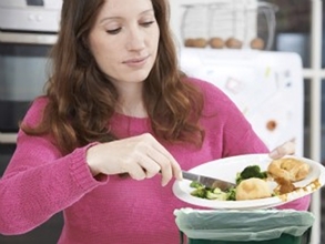 Woman scraping food waste into a pail on her counter.